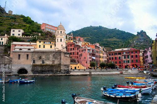 Harbor with small boats, waterfront and colorful houses with towers in the evening in the town of Vernazza in the Cinque Terre (Italy).