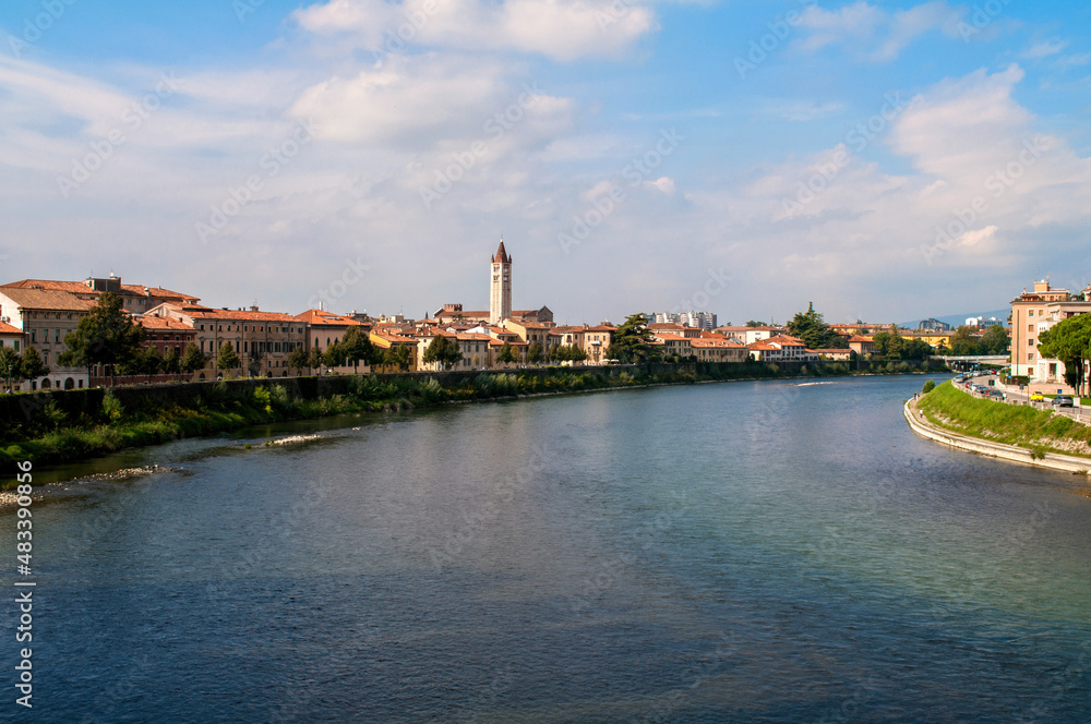 The river Adige in the Italian city of Verona. Waterfront with houses and a church tower.