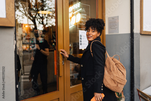 Black woman with backpack entering restaurant