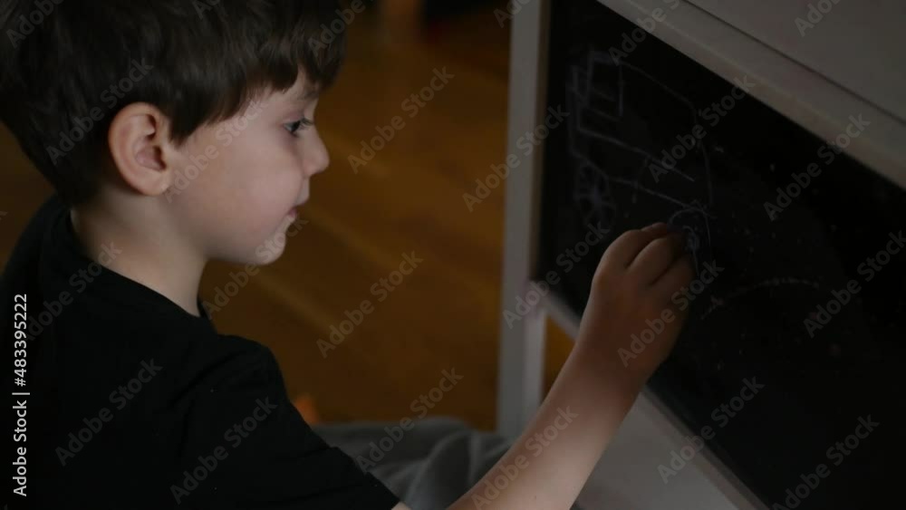 a five-year-old boy at home draws with chalk on a slate a five-year-old boy at home draws with chalk on a slate