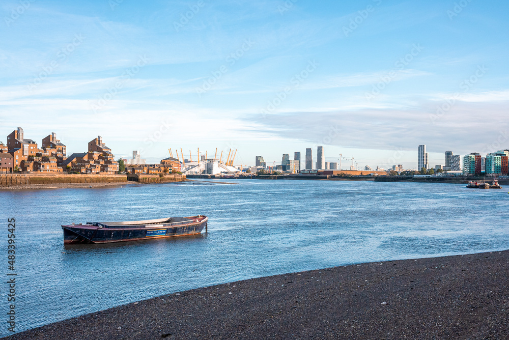 Obraz premium Boat moored on coast with financial district city skyline in background against sky, Boat moored along riverbank