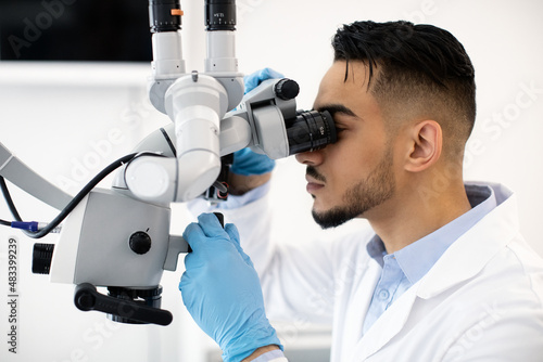 Young Arab Dentist Doctor Using Dental Microscope At Workplace In Clinic