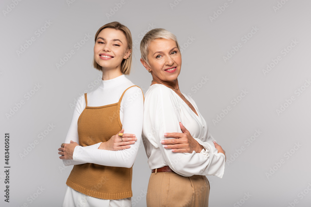 happy middle aged mother and joyful young daughter standing with crossed arms isolated on grey happy middle aged mother and joyful young daughter standing with crossed arms isolated on grey