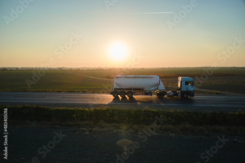 Aerial view of blurred fast moving cement cargo truck driving on highway hauling goods. Delivery transportation and logistics concept