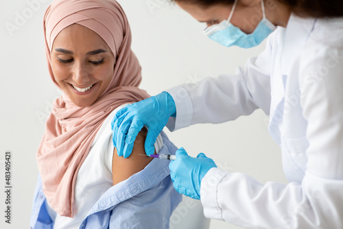 Leinwand Poster Closeup Shot Of Female Doctor Making Coronavirus Vaccine Injection To Muslim Wom