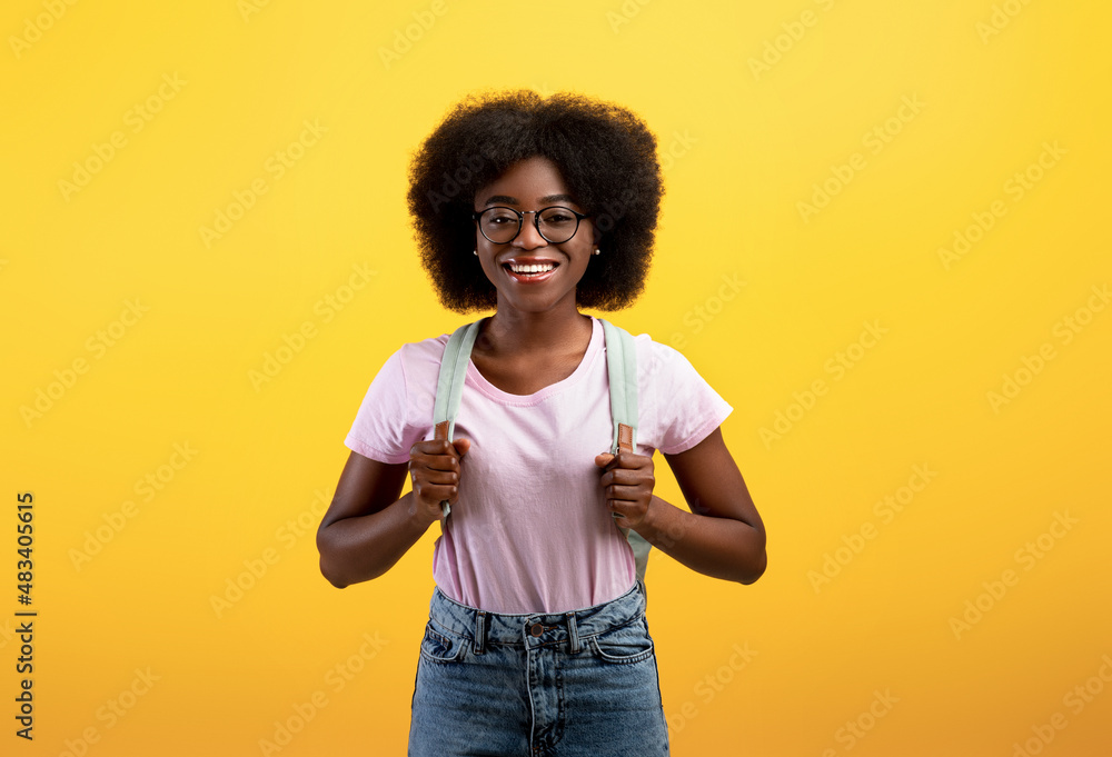 Happy african american female student with backpack posing over yellow studio background, ready for study Happy african american female student with backpack posing over yellow studio background, ready for study
