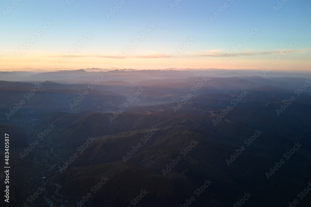 Aerial view of dark mountain hills at sunset. Hazy peaks and misty valleys in evening Aerial view of dark mountain hills at sunset. Hazy peaks and misty valleys in evening
