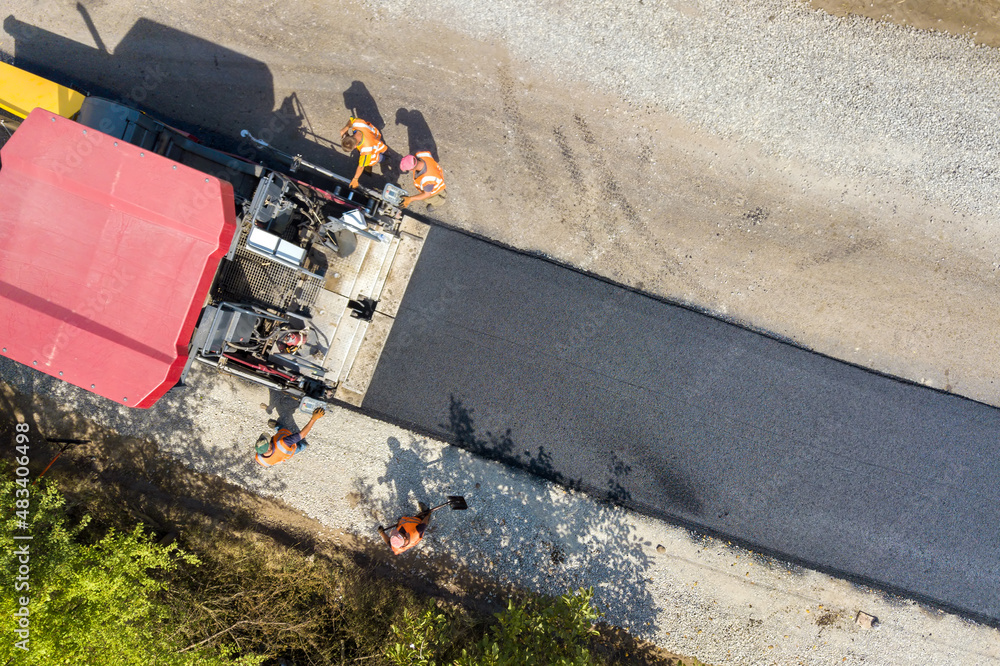 Aerial view of new road construction with asphalt laying machinery at work.