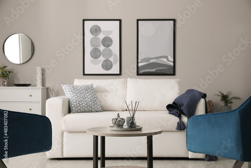 Stylish living room interior with white sofa  armchairs and small coffee table