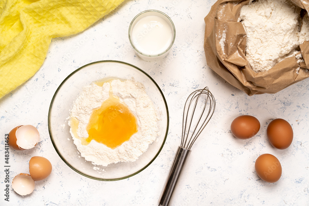 the process of making dough for pancakes with ingredients on a light table, eggs and flour are whipped with a mixer