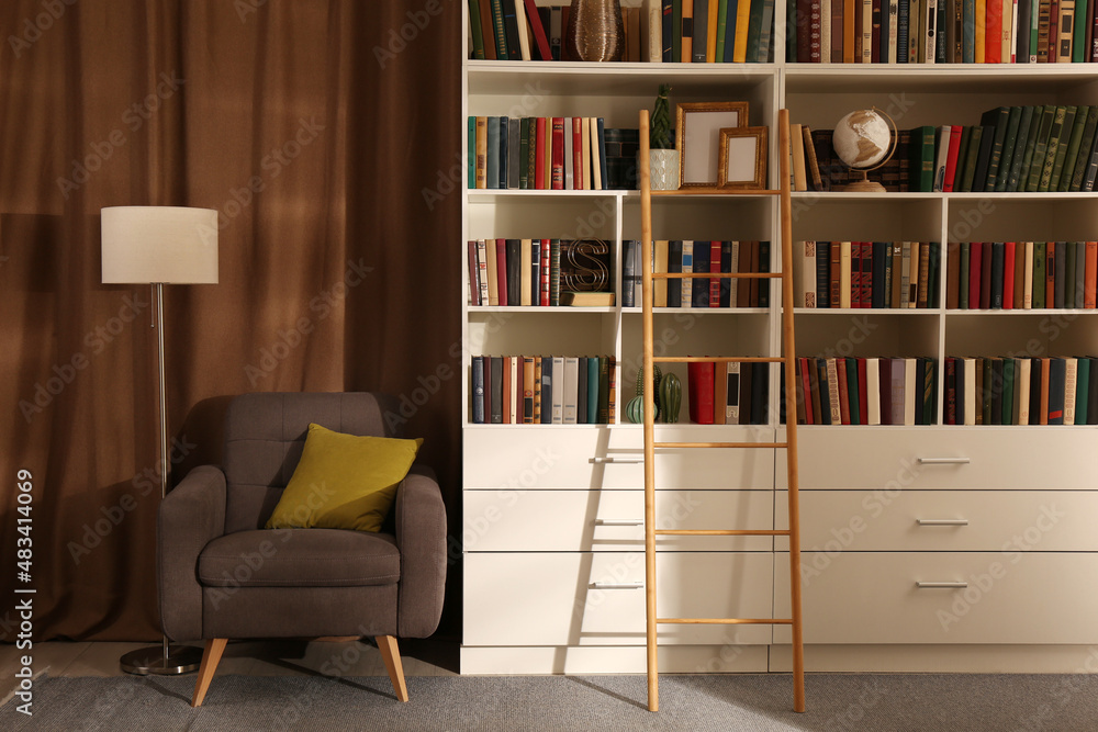 Cozy home library interior with collection of different books on shelves and comfortable place for reading Cozy home library interior with collection of different books on shelves and comfortable place for reading