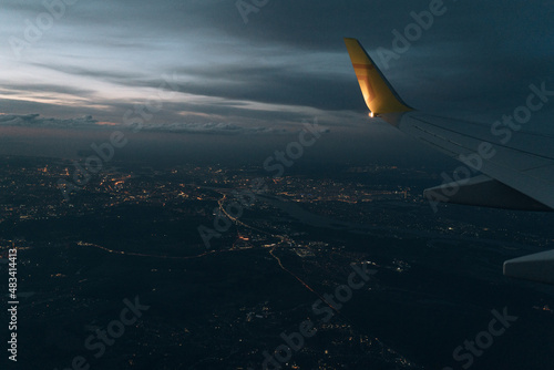 View from the plane on the wing of an airplane flying over the night city