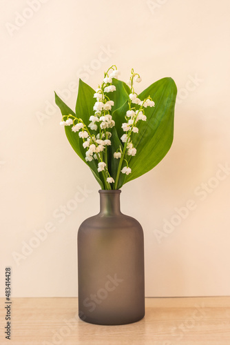 Bouquet of flowers lily of the valley in vase on table. Beautiful vertical card on International Women's Day, Mother's day or birthday, space for text.