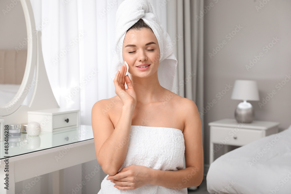 Beautiful young woman with hair wrapped in towel cleaning her face at home Beautiful young woman with hair wrapped in towel cleaning her face at home