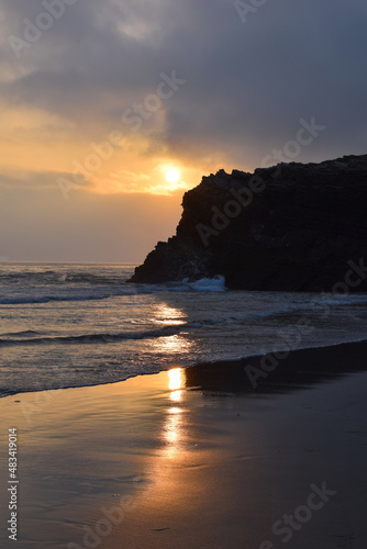 sunset on the beach with a rock in the landscape