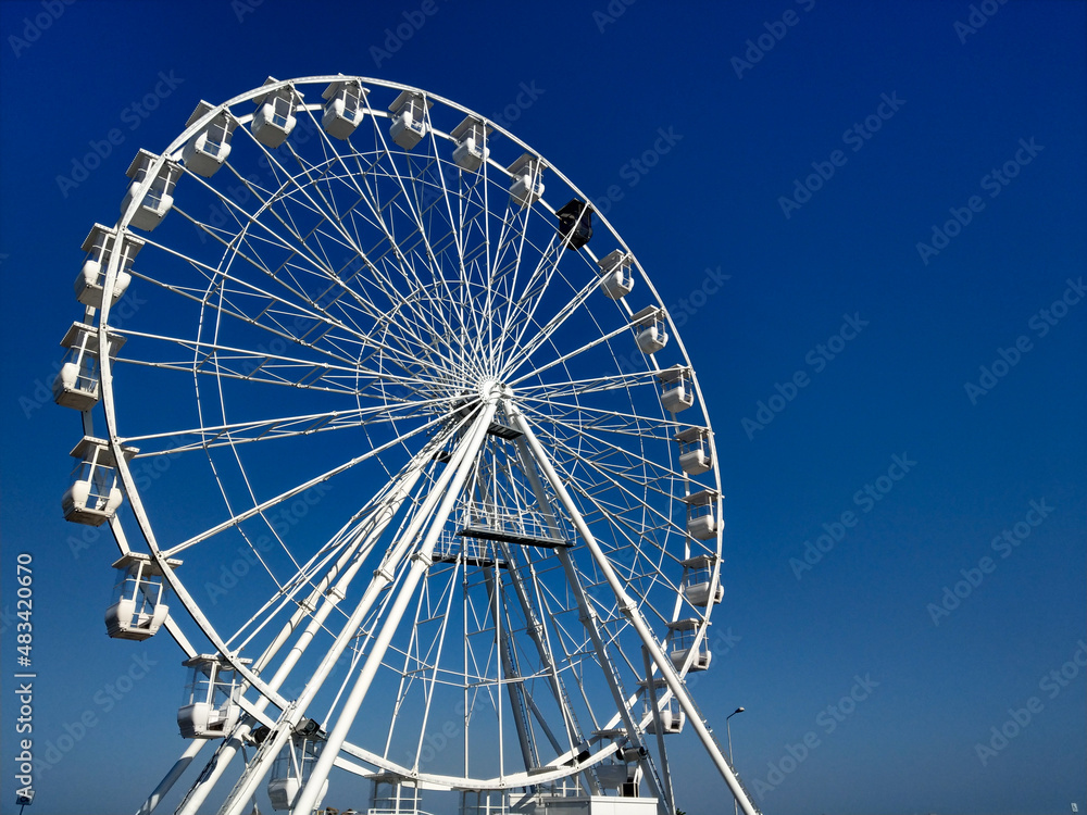 A yellow scouter with the Constanta Ferris Wheel and clear blue sky in the background on a sunny day.