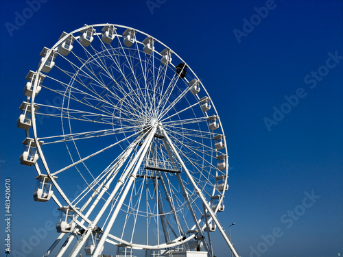 A yellow scouter with the Constanta Ferris Wheel and clear blue sky in the background on a sunny day.