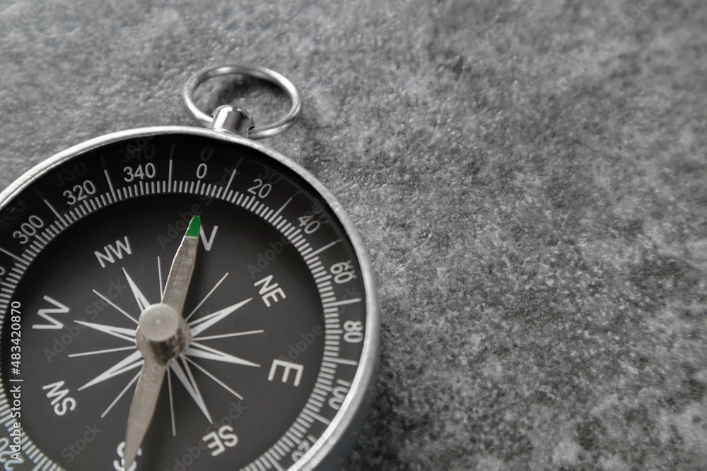 Close up of magnetic compass with black dial laying on stone surface and arrow pointing north, selective focus. Travel and tourism concept. Close up of magnetic compass with black dial laying on stone surface and arrow pointing north, selective focus. Travel and tourism concept.