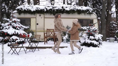 Mom and daughter are jumping in the snow holding hands