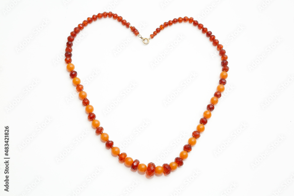 Amber beads in the form of a heart on a white background. Jewelry cutting. Sun stone. Jewelry material. Ancient fossilized resin. Copal. Crystal. Fashion and beauty. Amber beads in the form of a heart on a white background. Jewelry cutting. Sun stone. Jewelry material. Ancient fossilized resin. Copal. Crystal. Fashion and beauty.