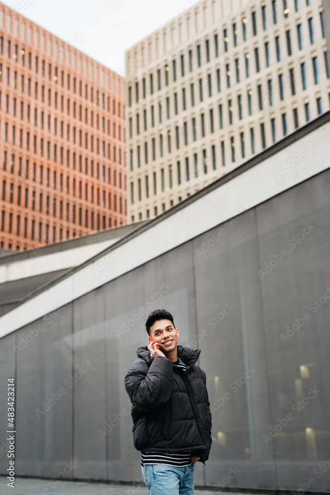 Young man walking and talking on a red smartphone on the street Young man walking and talking on a red smartphone on the street