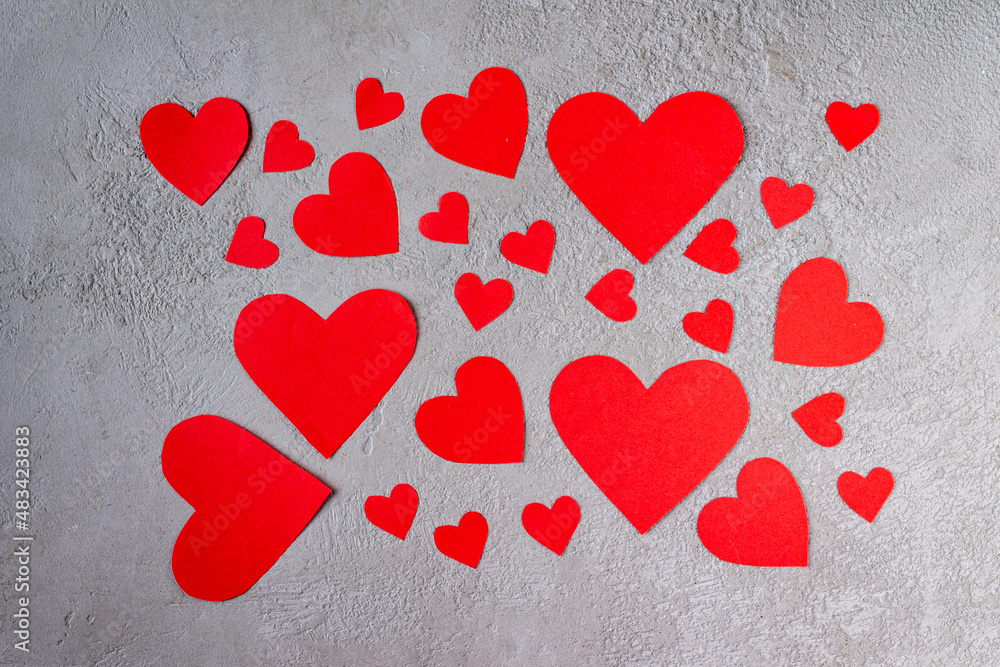 red paper hearts scattered over gray plaster red paper hearts scattered over gray plaster
