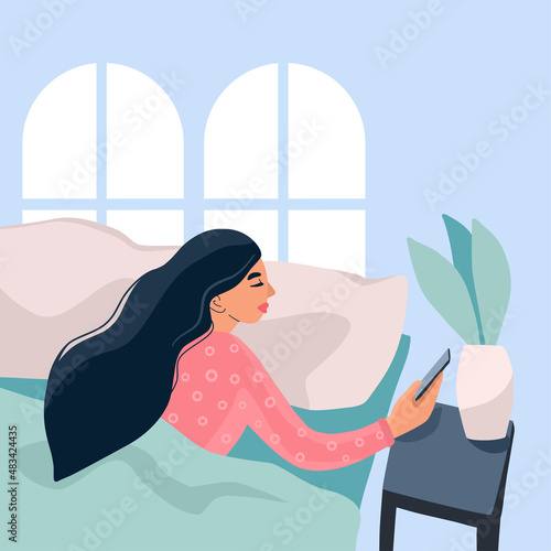 Happy young girl wakes up in the morning. Girl holding her smartphone while in bed. Good morning. Daily Routine Activities. Regular start of the day. 