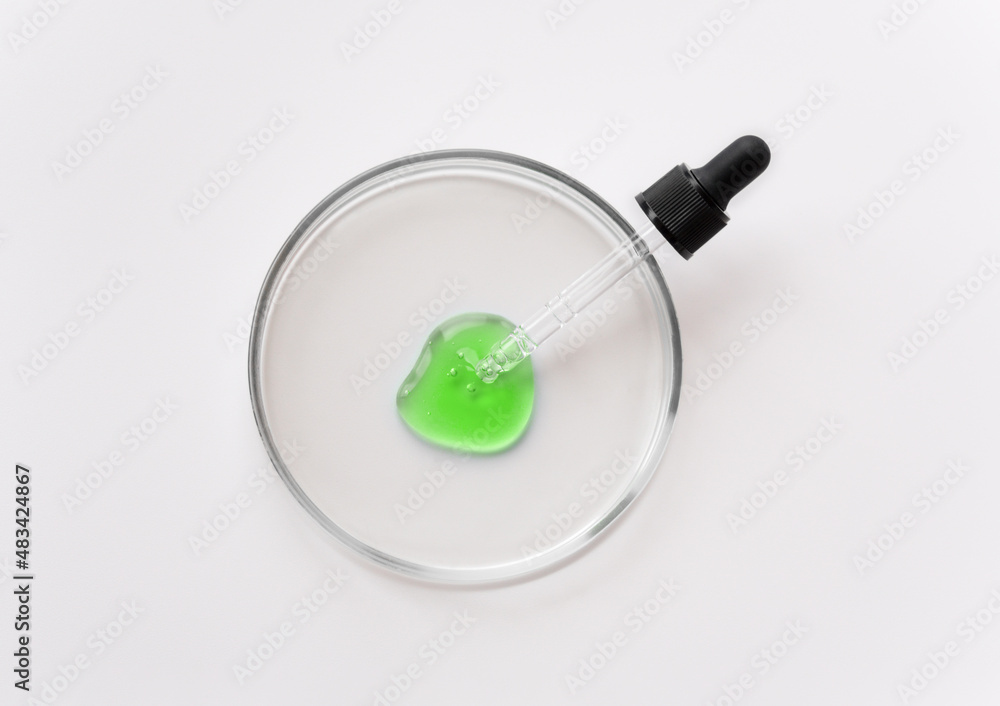 Laboratory glass petri with pipette and green drop of serum, oil, beauty product. Natural medicine, cosmetic research, bio science. Concept of skincare and analysis. Dermatology. Flat lay, top view Laboratory glass petri with pipette and green drop of serum, oil, beauty product. Natural medicine, cosmetic research, bio science. Concept of skincare and analysis. Dermatology. Flat lay, top view