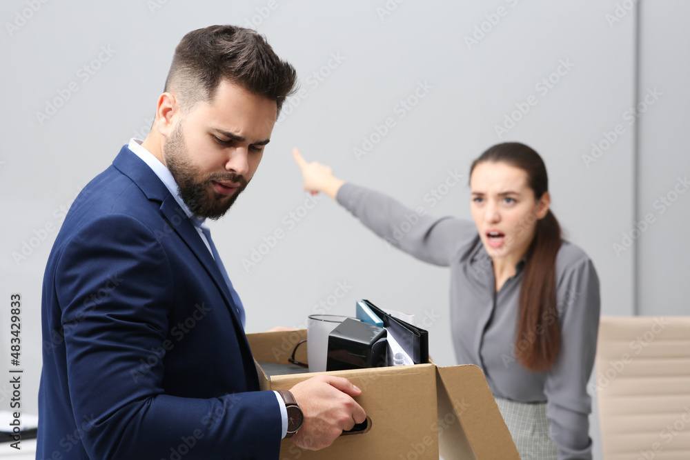 Boss dismissing young man from work in office Boss dismissing young man from work in office