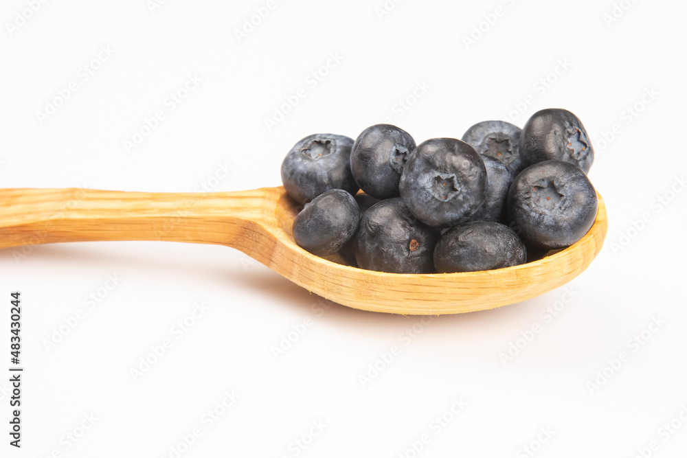 fresh blueberries lie in a wooden spoon on a white background. vitamin organic food fresh blueberries lie in a wooden spoon on a white background. vitamin organic food
