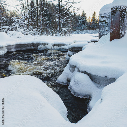 Water flow of a small snow-covered forest river, ice fragments close-up. Long exposure. Global warming concept, ecology, environmental conservation, graphic resources, macro photography