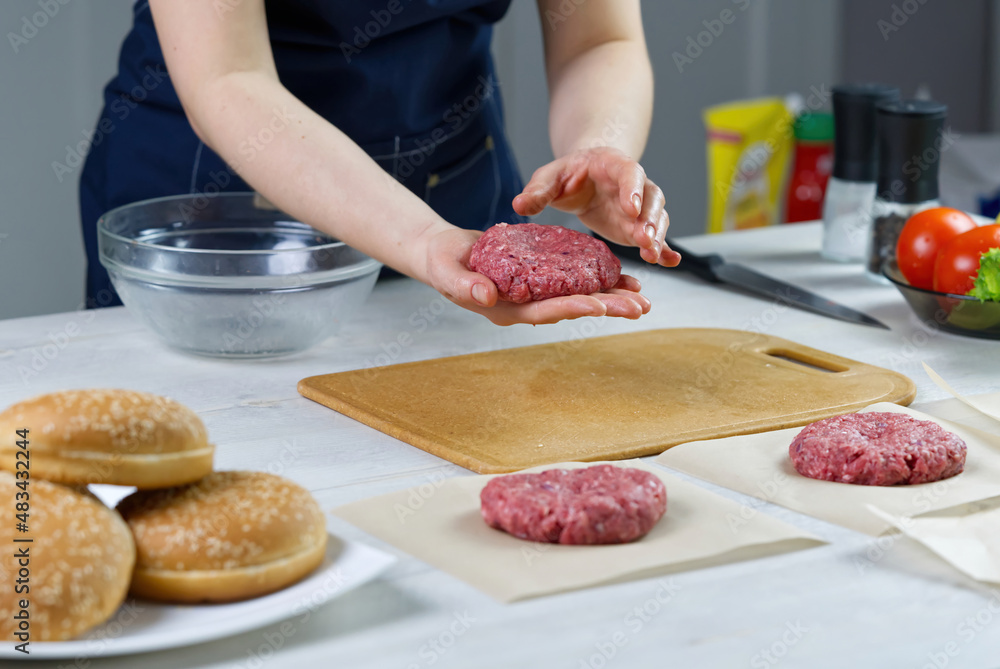 Woman's hand forming a beef meat for a hamburger party. Portioning ground meat. Homemade burgers. Making food at home. close up