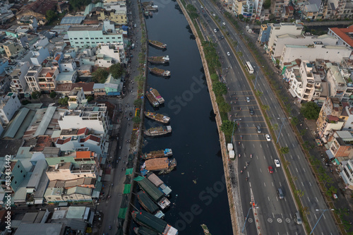 Vietnamese Lunar New Year floating flower market in Ho Chi Minh City is a highlight of the Tet festival. Drone view of bridge and Farmer Boats with flowers line the busy urban canal in morning light.