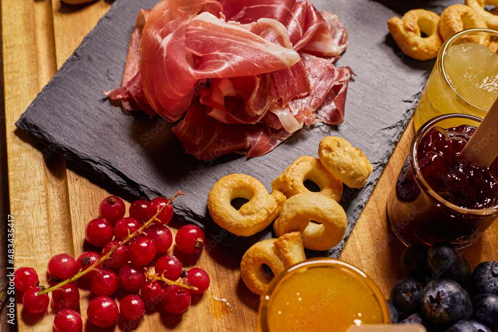 Fototapeta premium Wooden cutting board with cold cuts and cheeses