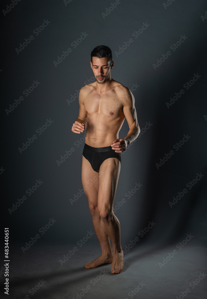 Sexy man with a muscular body posing naked with black underpants inside a studio