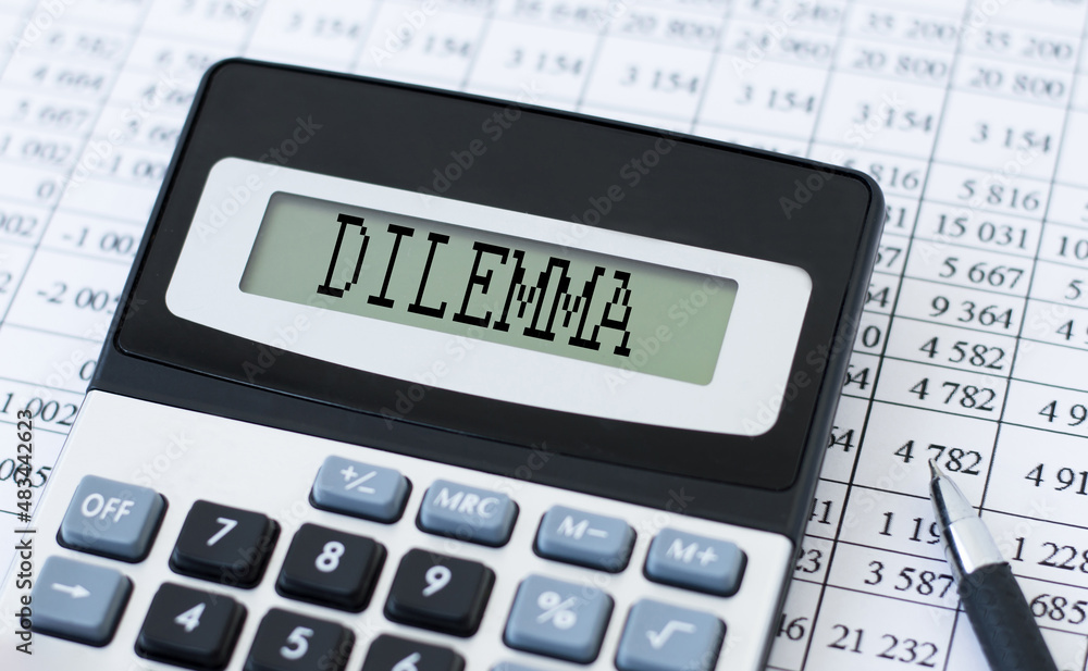 Calculator with text DILEMMA on the screen on the background of financial statements next to it is a pen Calculator with text DILEMMA on the screen on the background of financial statements next to it is a pen
