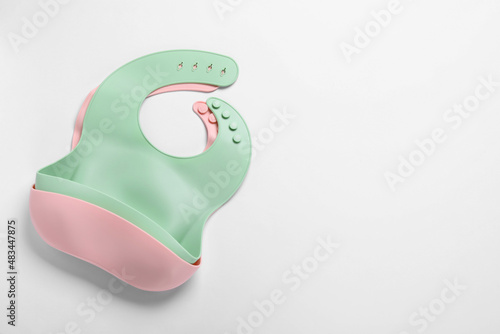 Color silicone baby bibs on white background, top view