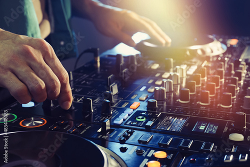 DJ creating music on modern console mixer in night club, closeup