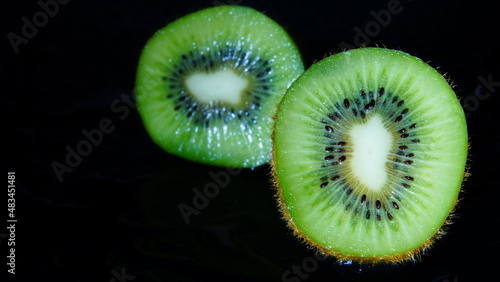 Sliced ​​wet kiwi in the dark abstraction
