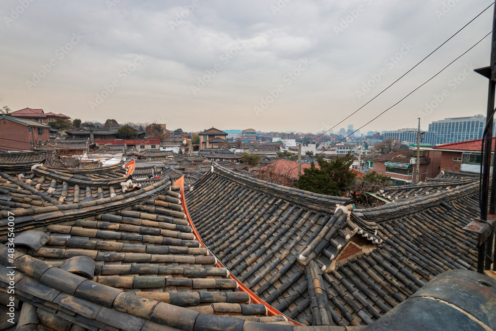 Fototapeta premium View above old buildings with traditional Korean roof tiles at Bukchon Hanok Village in Seoul, South Korea.
