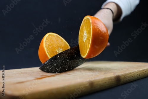 Slicing orange on a wooden board with knife