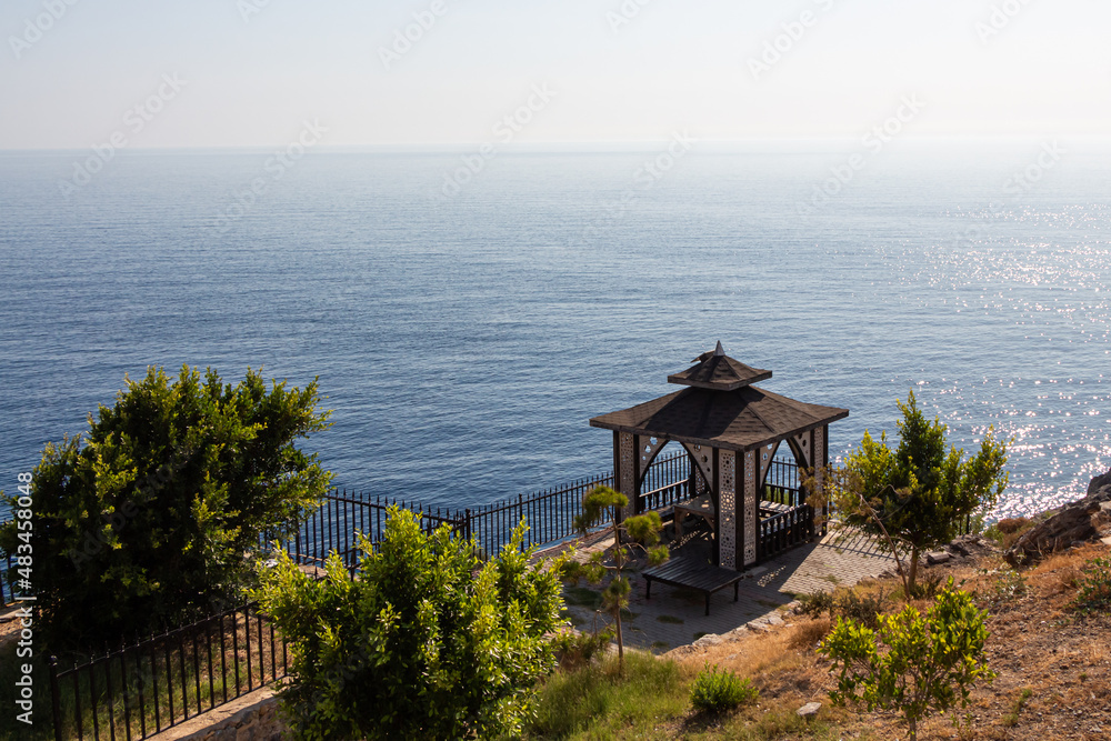 Beautiful wooden pavilion and green plants are on the beach by the blue sea