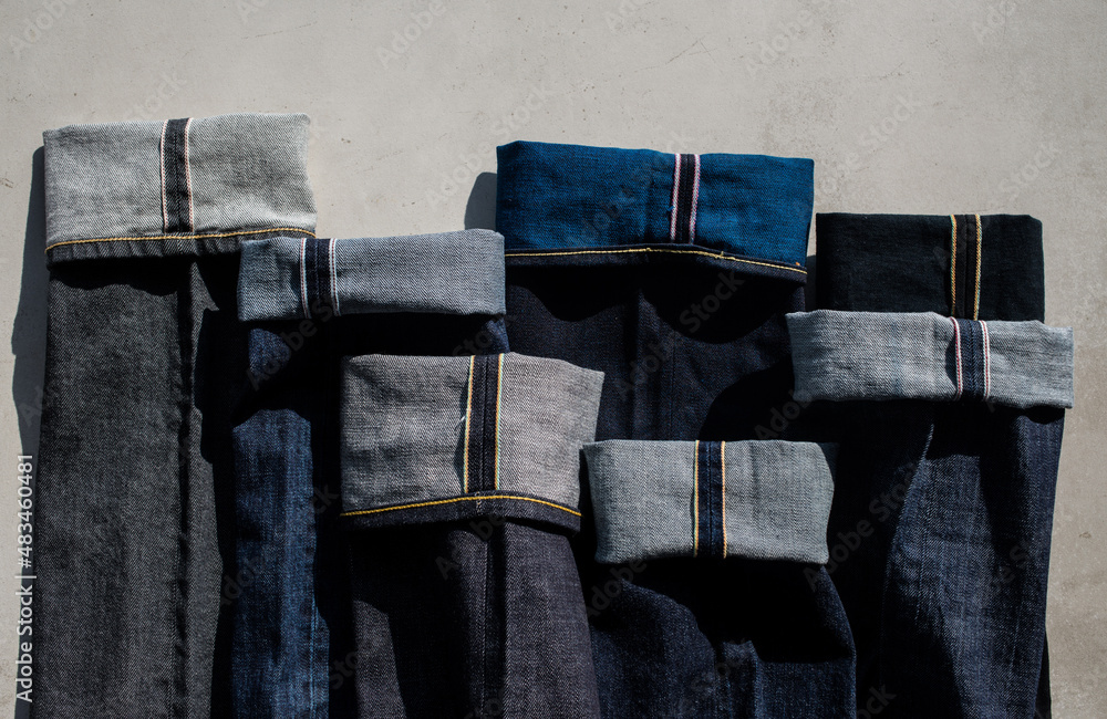 Variety of denim on a gray background. Selvage denim. Denim background. Pants are blue. Close-up