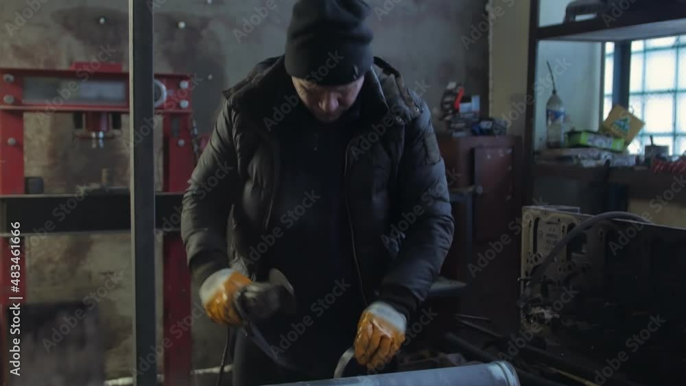 A man cuts a pipe with a grinder with sparks A man cuts a pipe with a grinder with sparks
