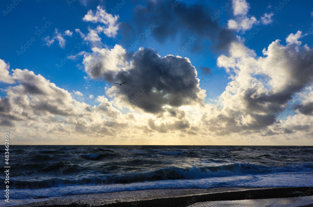 Panoramic view of Baltic sea from sandy shore, sand dunes. Dramatic sky with glowing clouds, sunbeams. Denmark