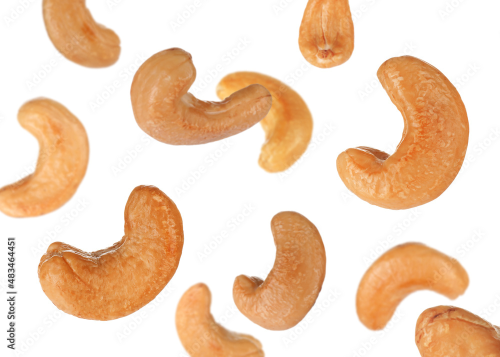 Tasty roasted cashew nuts falling on white background