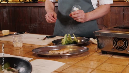 The chef on the stream prepares a dish of fried fish with broccoli and sauce