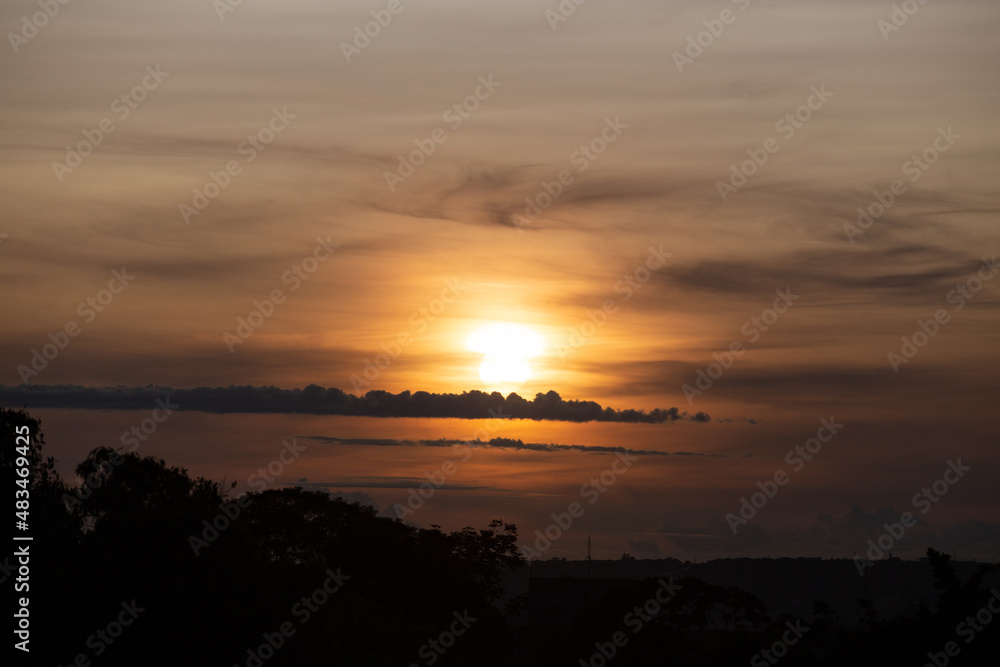 Sunrise on the horizon with orange sky and sparse clouds