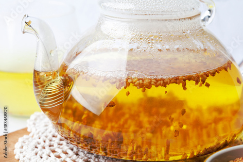 Glass teapot with buckwheat tea. Borosilicate glass teapot with spiral strainer photo