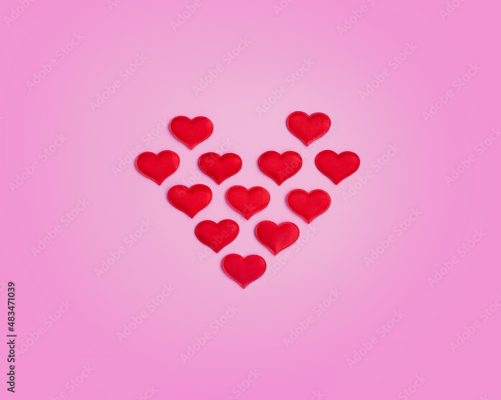 heart shape made up of small red hearts on a pink background. View from above